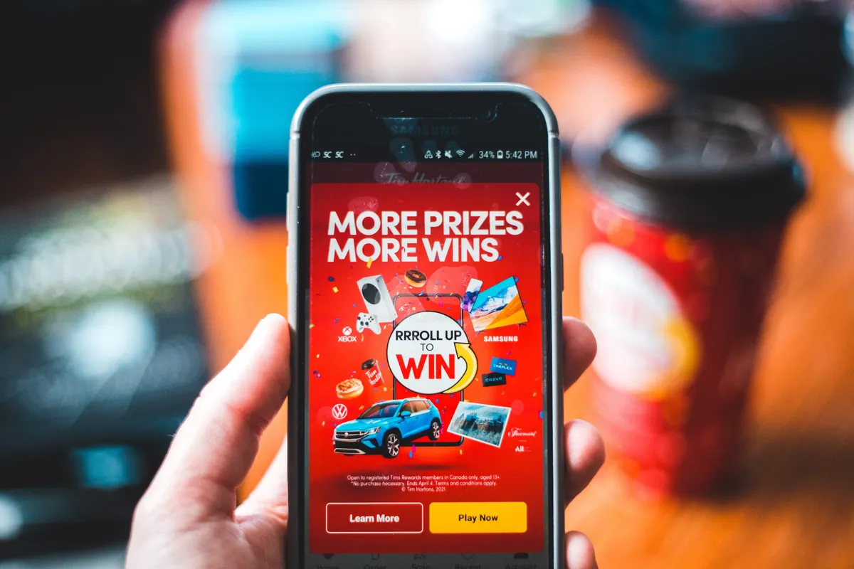 Hand holding a phone showing a More Prizes More Wins giveaway contest screen