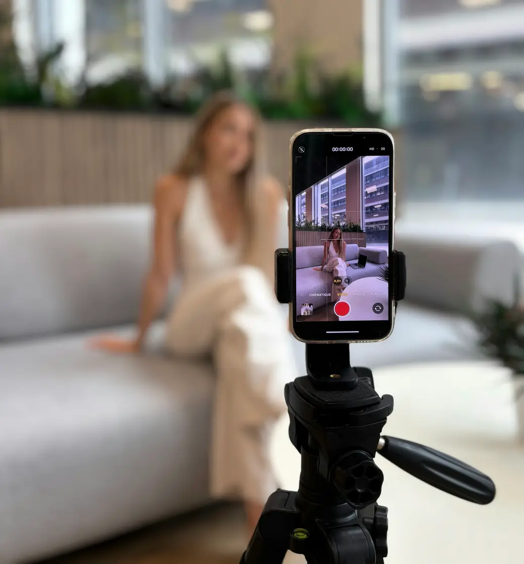 Smartphone on a tripod recording a woman on a sofa for a follow-up video