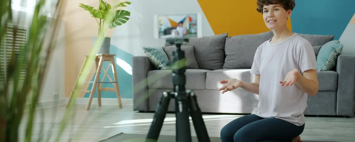 TikTok creator filming herself with a phone on a tripod in a bright living room